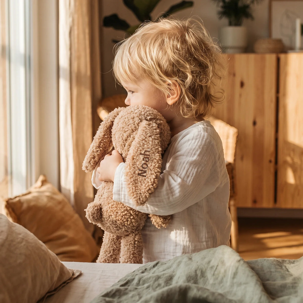 Kleinkind hält den beigen Kuschelhasen mit dem Namen „Noah“ im Arm