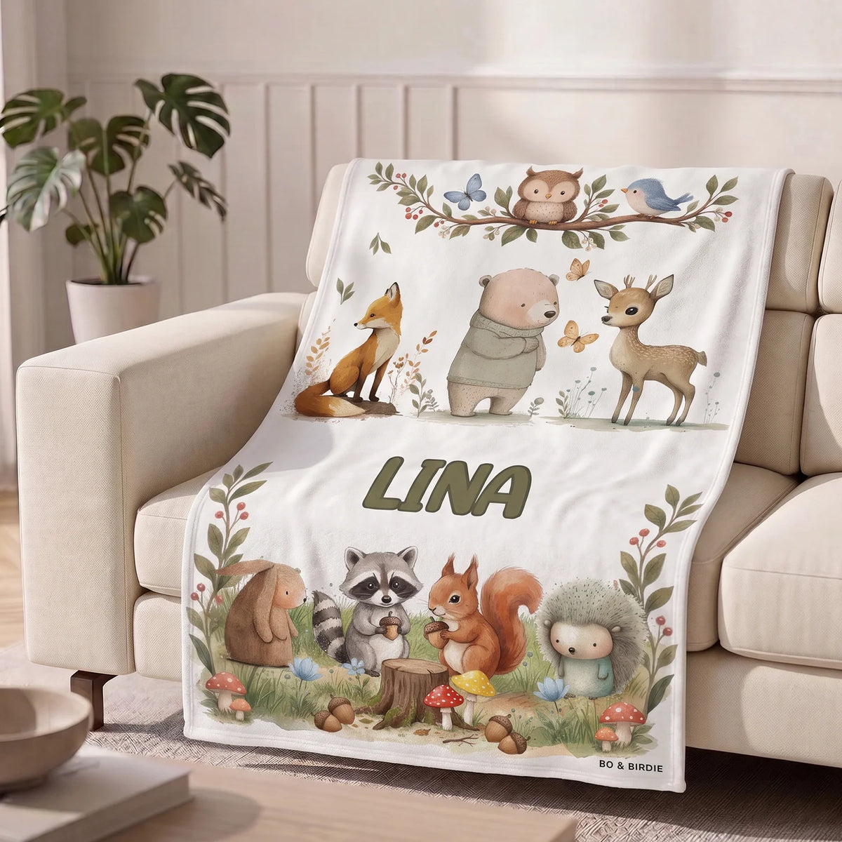 Helle Waldtiere-Decke mit dem Namen Lina auf einem Sofa