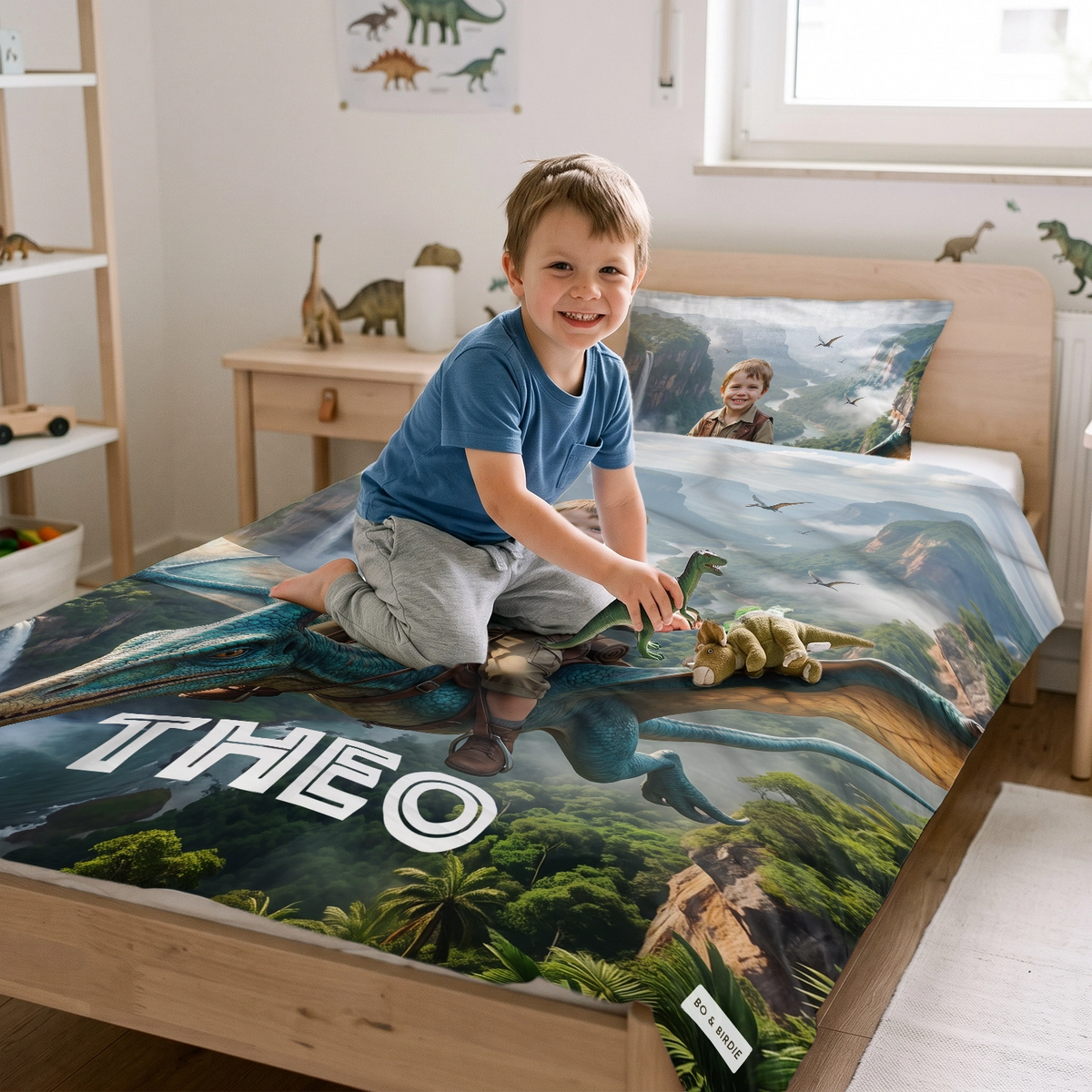 Junge sitzt auf dem Bett mit der Flugsaurier-Bettwäsche