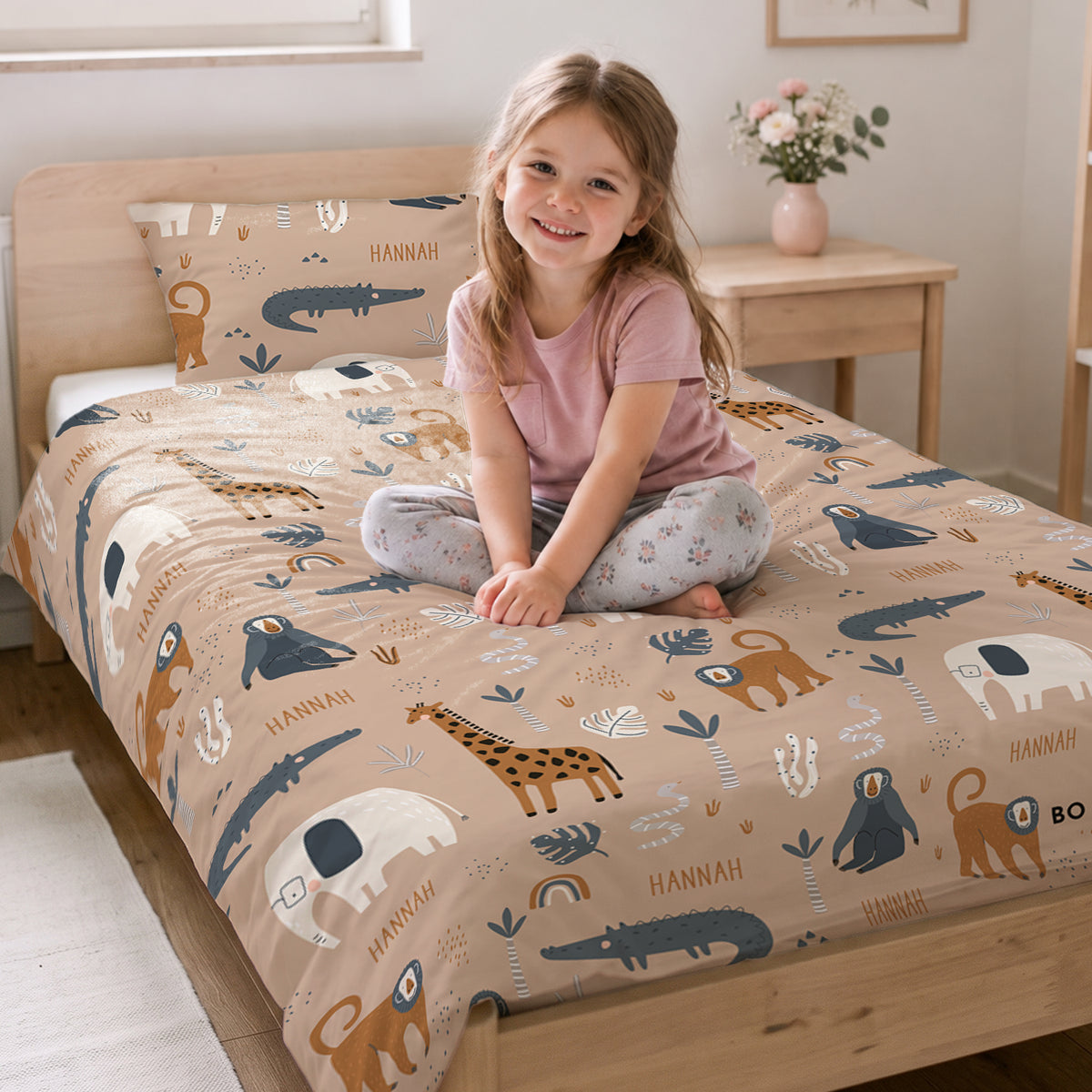 Mädchen sitzt auf dem Bett mit der Savannen-Bettwäsche