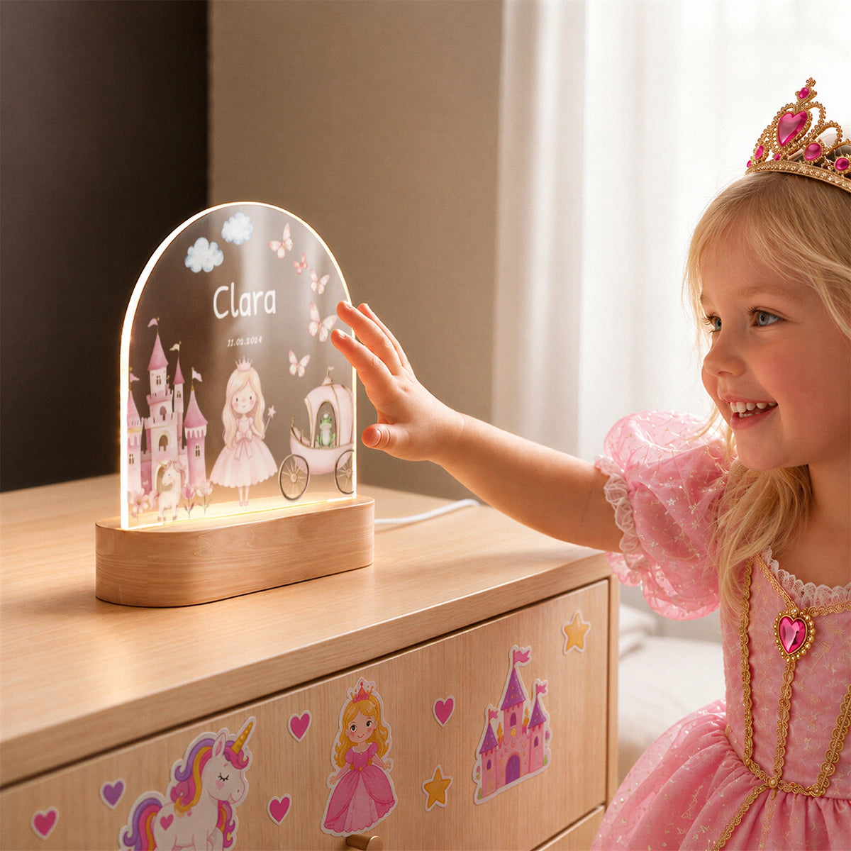 Mädchen mit Krone berührt das Prinzessin-Nachtlicht auf der Kommode