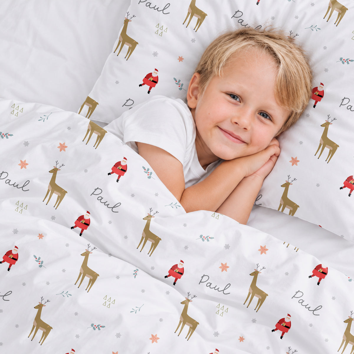 Junge liegt lächelnd auf der Weihnachts-Bettwäsche