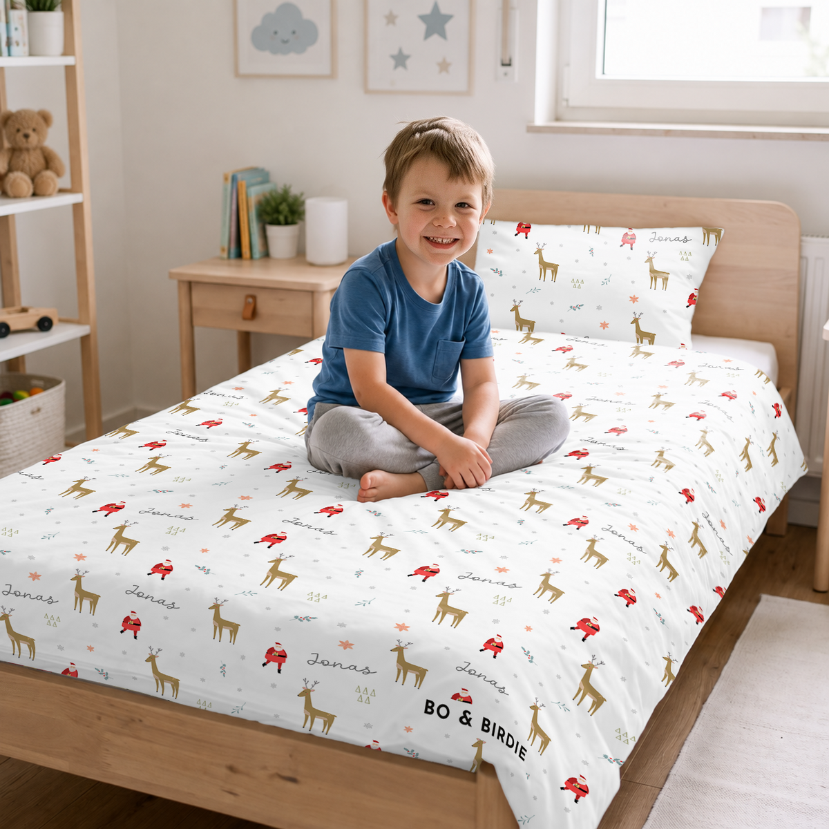 Junge sitzt auf dem Bett mit der Weihnachts-Bettwäsche