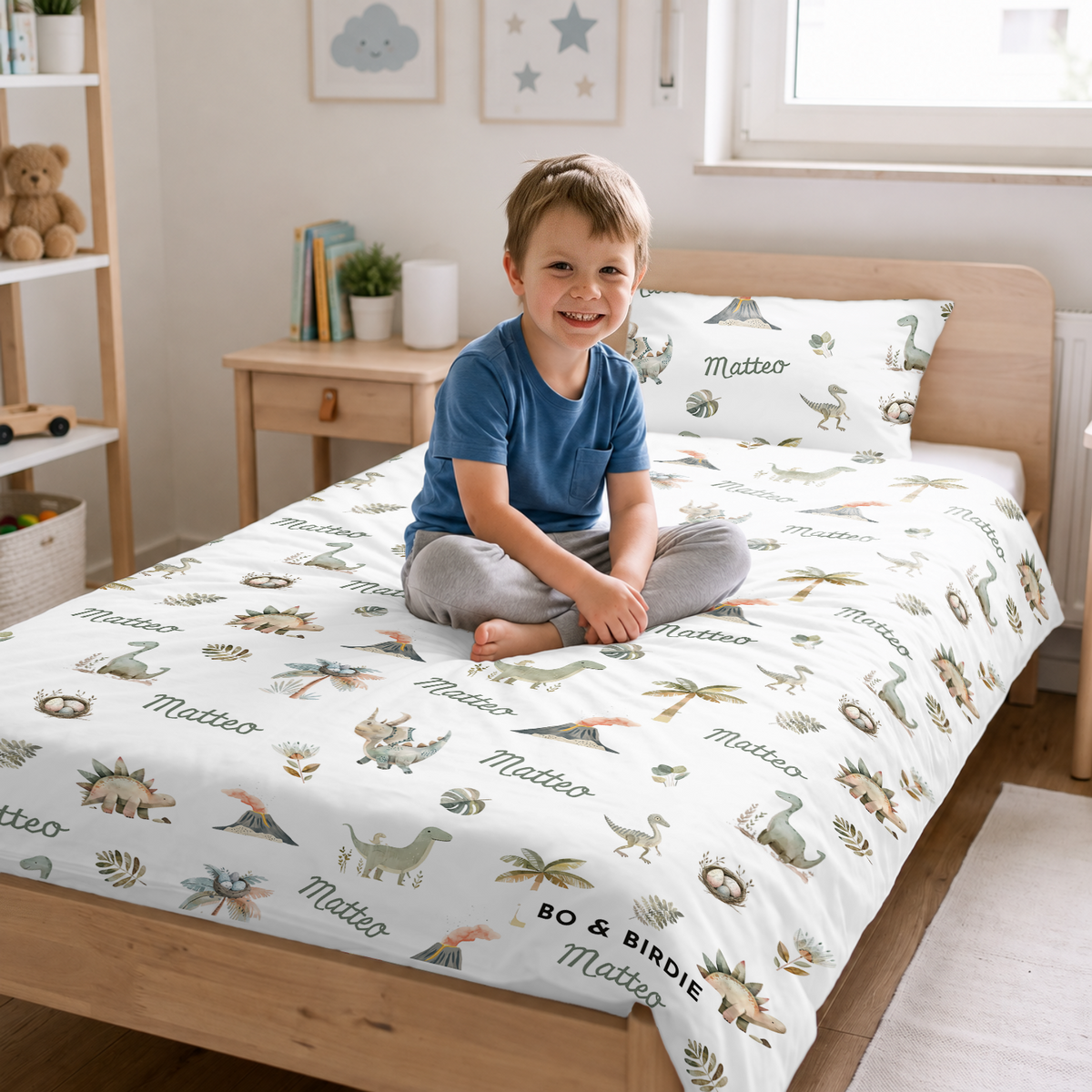 Junge sitzt auf dem Bett mit der Dino-Bettwäsche