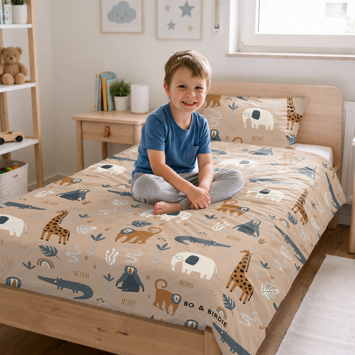 Junge sitzt auf dem Bett mit der Savannen-Bettwäsche
