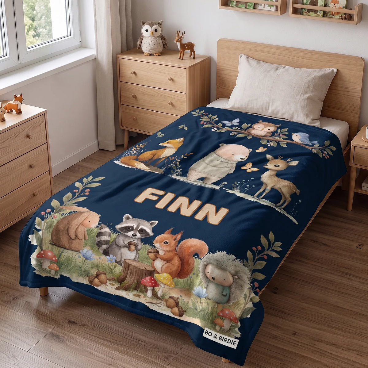 Dunkelblaue Waldtiere-Decke mit dem Namen Finn auf einem Kinderbett