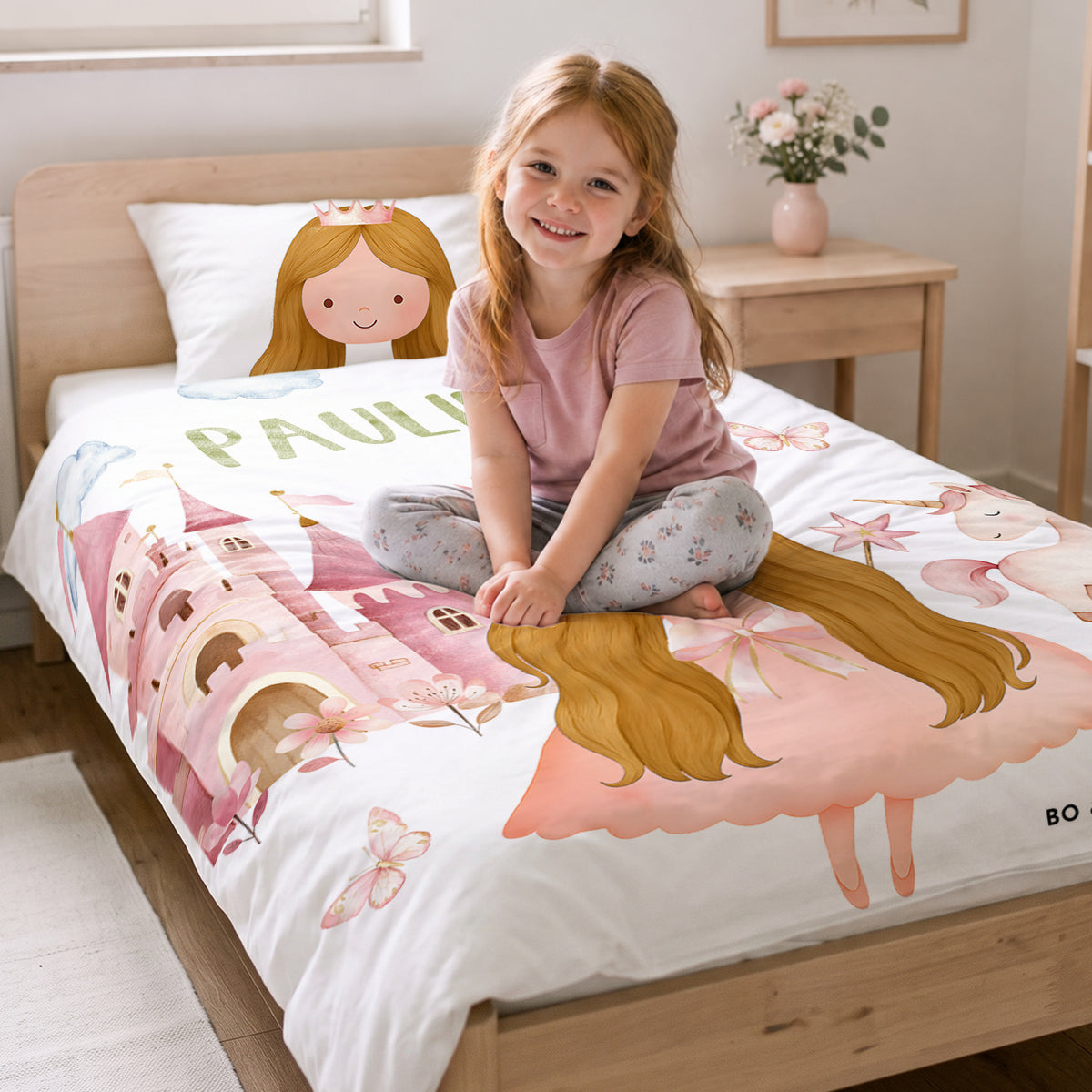 Mädchen sitzt auf dem Bett mit der Wunschprinzessin-Bettwäsche