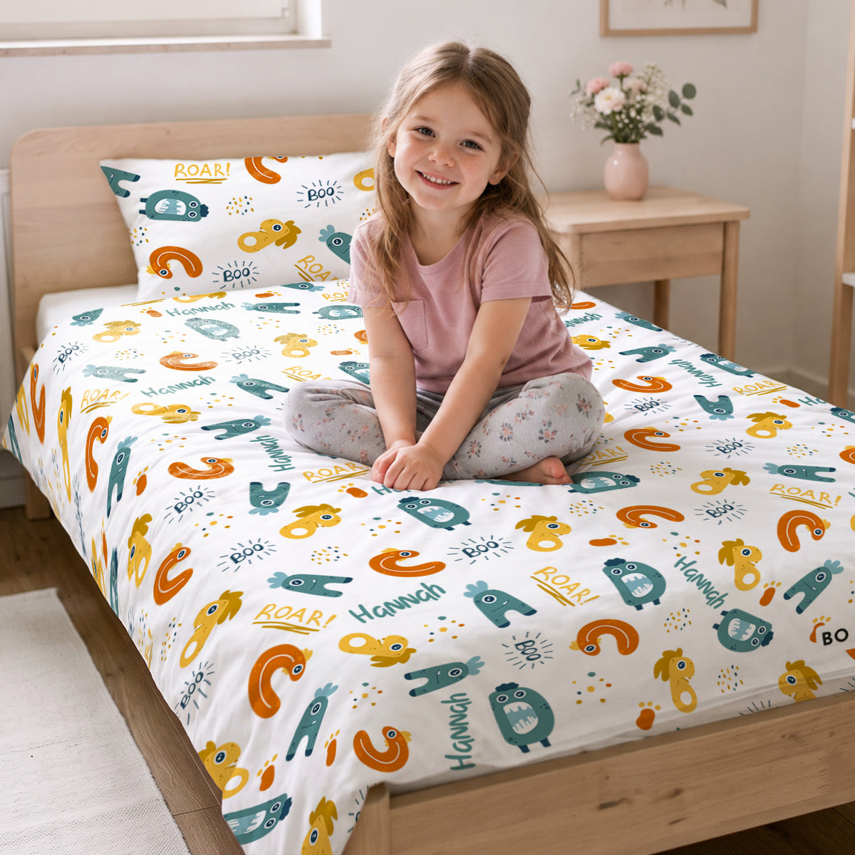 Mädchen sitzt auf dem Bett mit der Monster-Bettwäsche