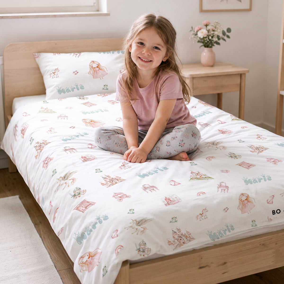 Mädchen sitzt auf dem Bett mit der Prinzessinnen-Kinderbettwäsche